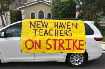 White mini van parked with yellow sign New Haven Teachers on Strike
