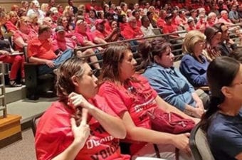 People sitting in a audience room filled to capacity looking ahead