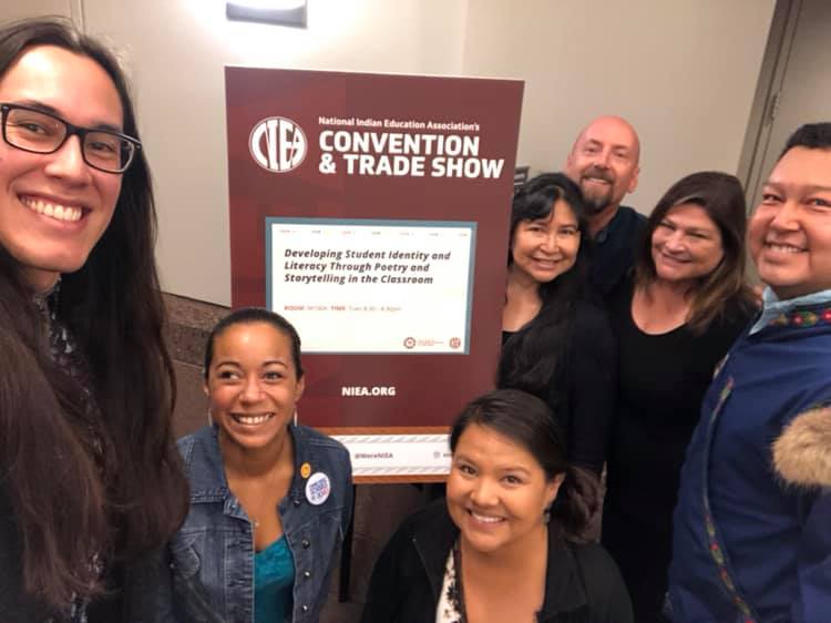 A group of Native American Caucus members standing around a sign smiling