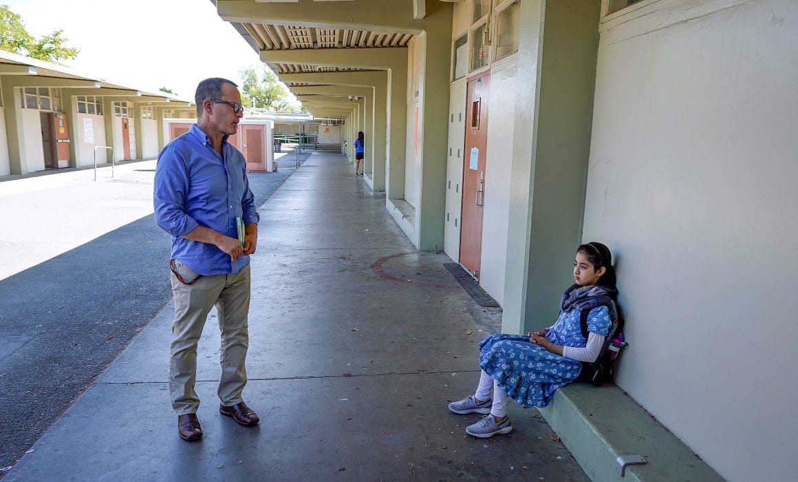 Student sitting on the floor against the wall and teacher standing