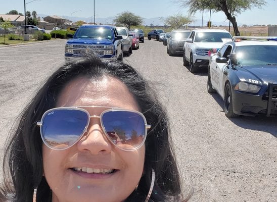 Teacher in sunglasses with row of cars behind