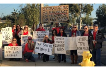 People outside holding up protest signs all wearing red in support of Cypress Teachers fair contract