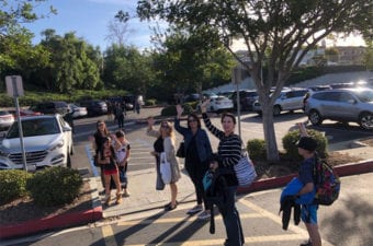 People waving outside in parking lot