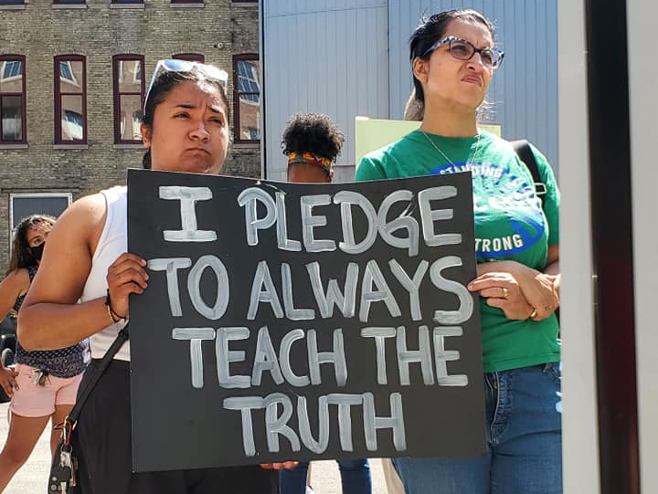 Teachers with sign "I pledge to always teach the truth"