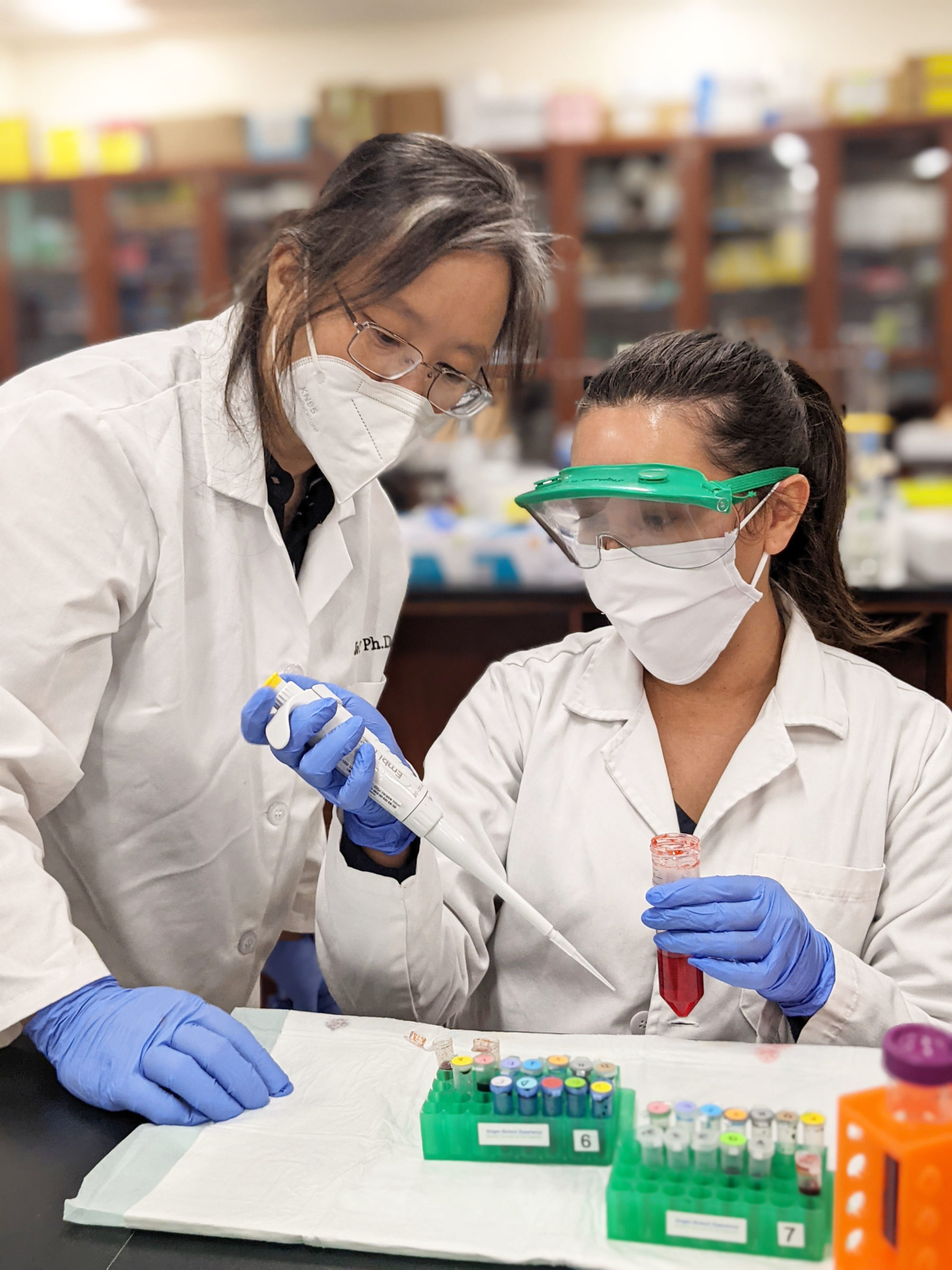 Wu with a student intern in lab coats working on a supply chain project.