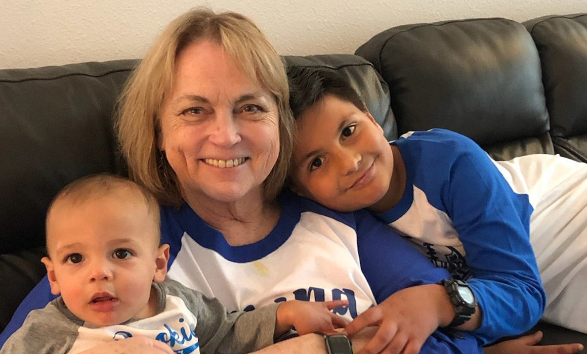 Mary Ambriz sitting on couch with two yong grandchildren.