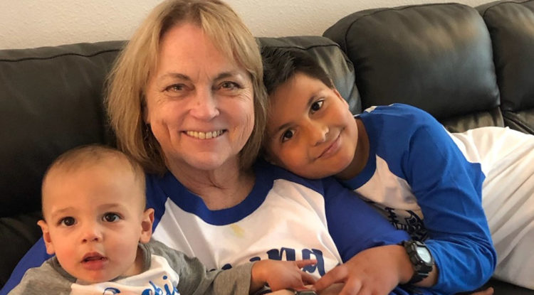 Mary Ambriz sitting on couch with two yong grandchildren.