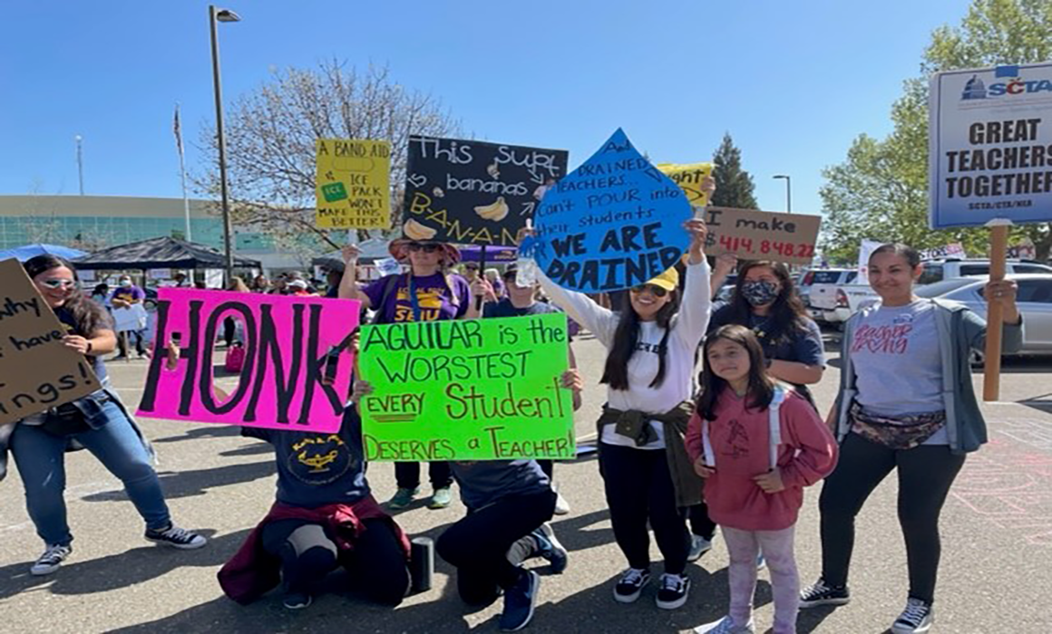 Educators hold signs to show support during the strike.