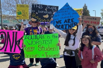 Educators hold signs to show support during the strike.