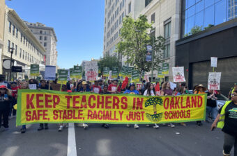 Protestors marching with a big yellow banner with red text