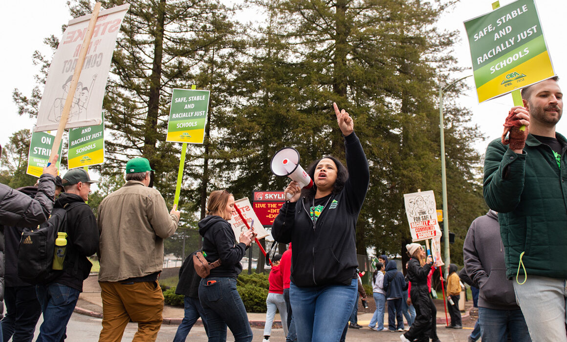 Protestors marching with green and yellow Oakland Educators picket signs