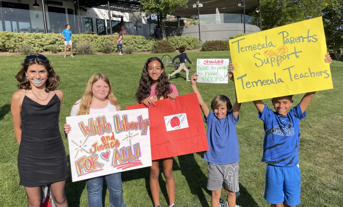 four students standing holding rally signs