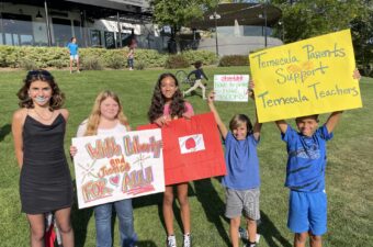 four students standing holding rally signs