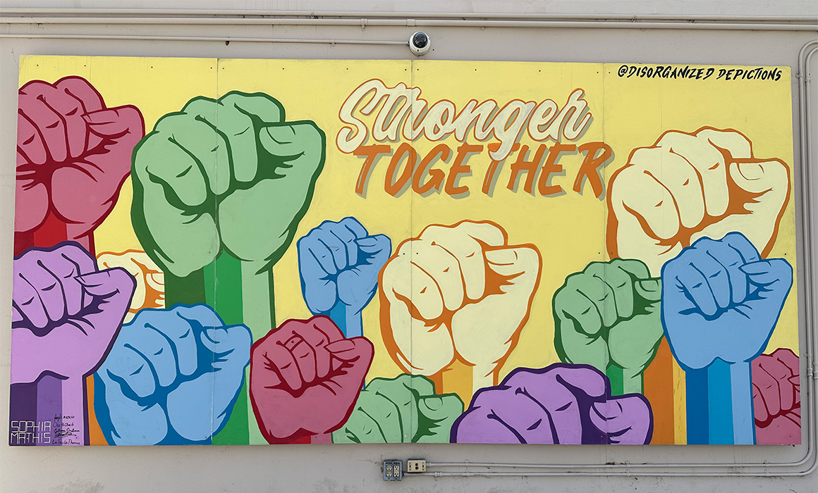 Image of a mural with the words "Stronger Together" and painted raised fists.