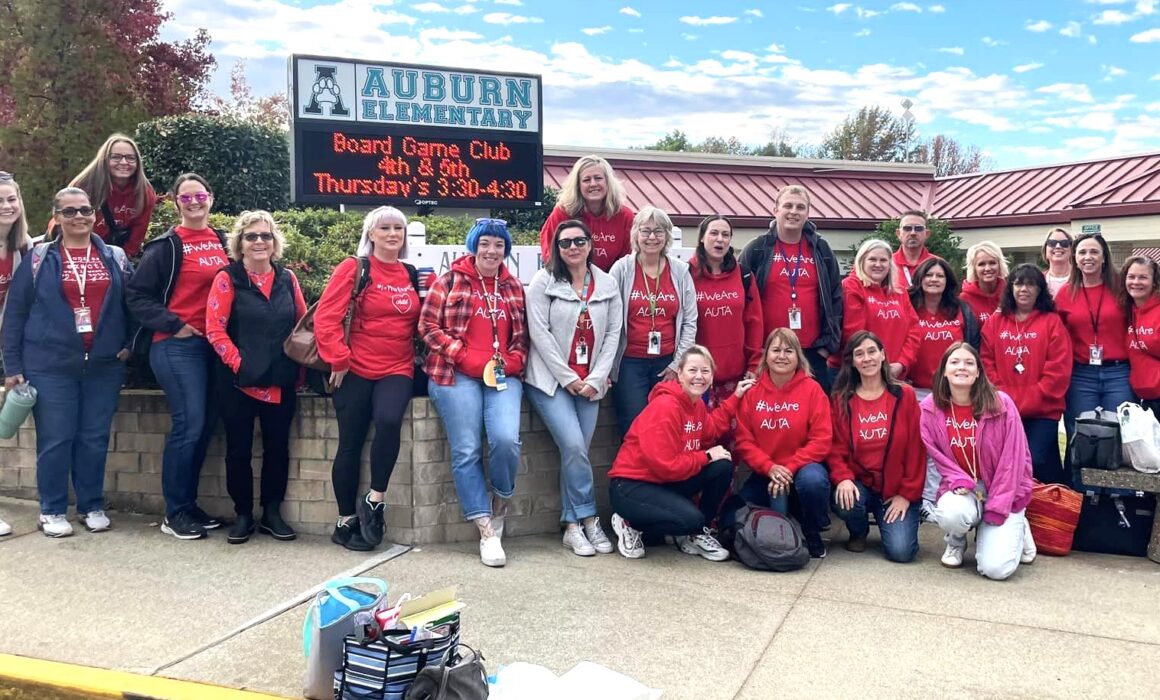 Auburn Elementary: Group of people in front of school sign.