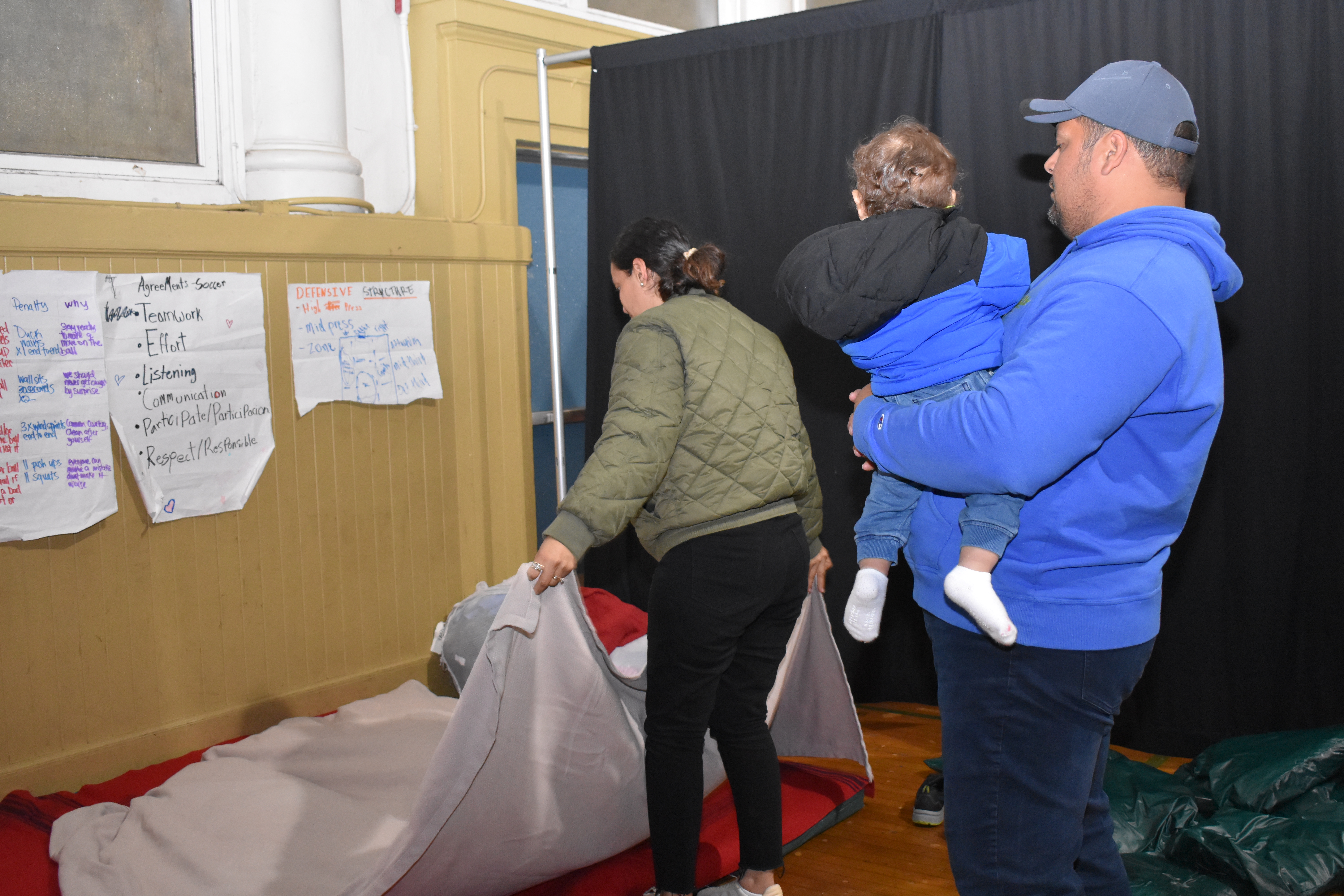 The Navas-Torrez family prepares their beds at the Buena Vista Horace Mann school gym