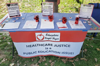 Photo of table with sign saying "Healthcare Justice is a Public Education Issue!"