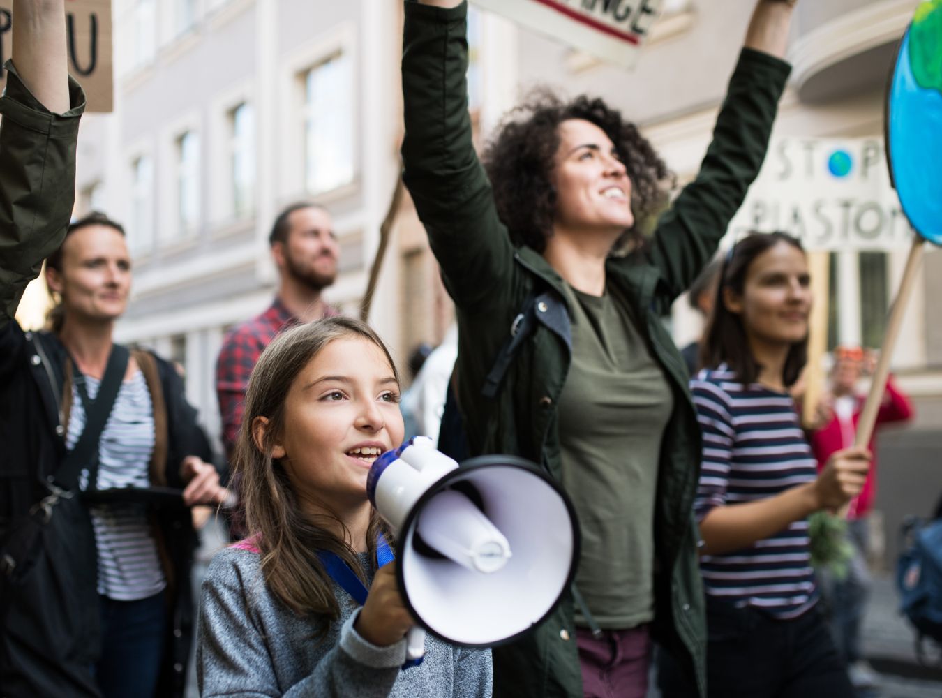 Photo of a oyung child holding a megaphone in a crowd f protesters. 