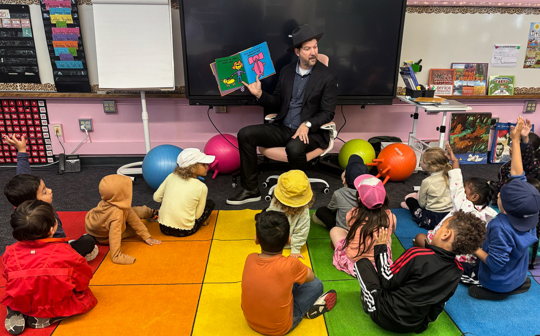 CTA President David Goldberg holding an open book sand reading to a classroom of small children. 