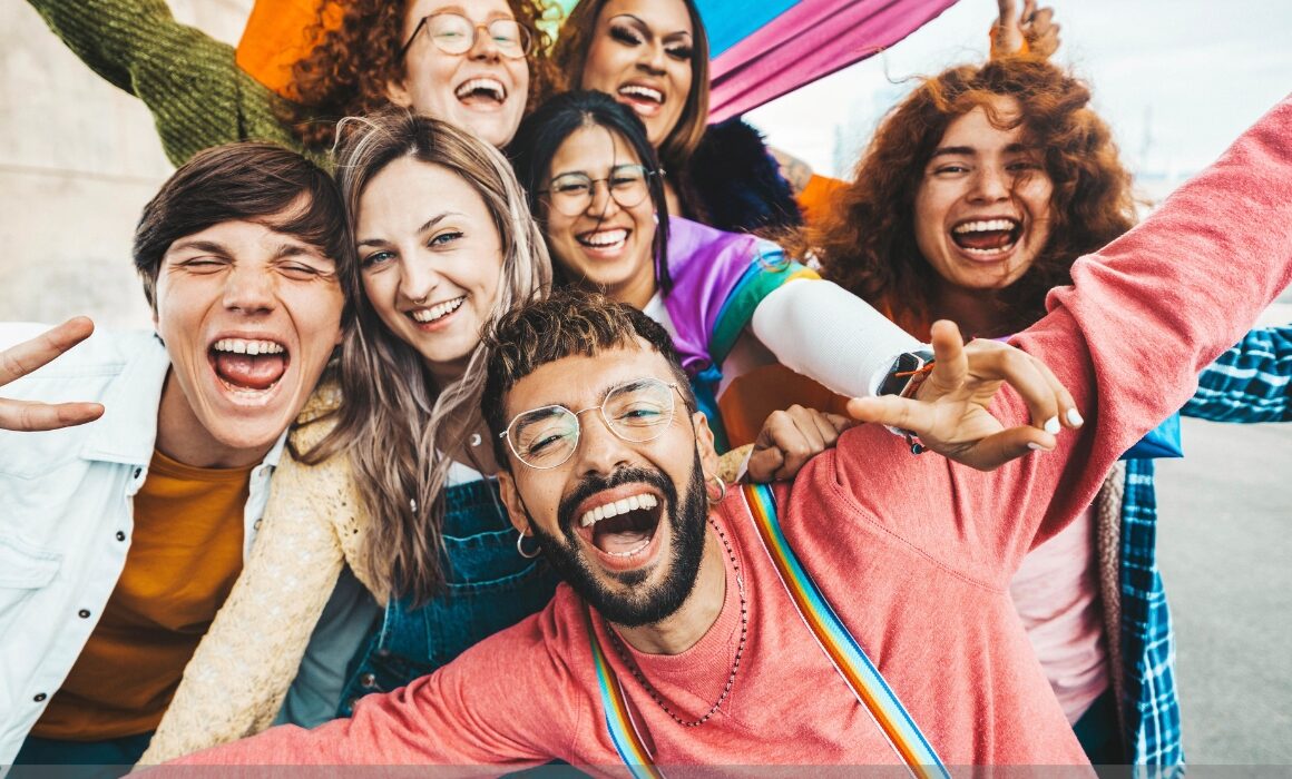 Graphic with an Image of people, a rainbow flag behind them, and the words Transgender Day of Visibility displayed.
