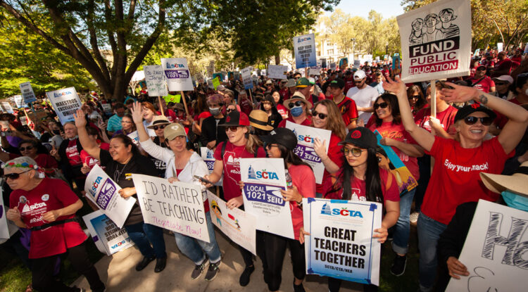 A large crowd of people holding up picket signs .
