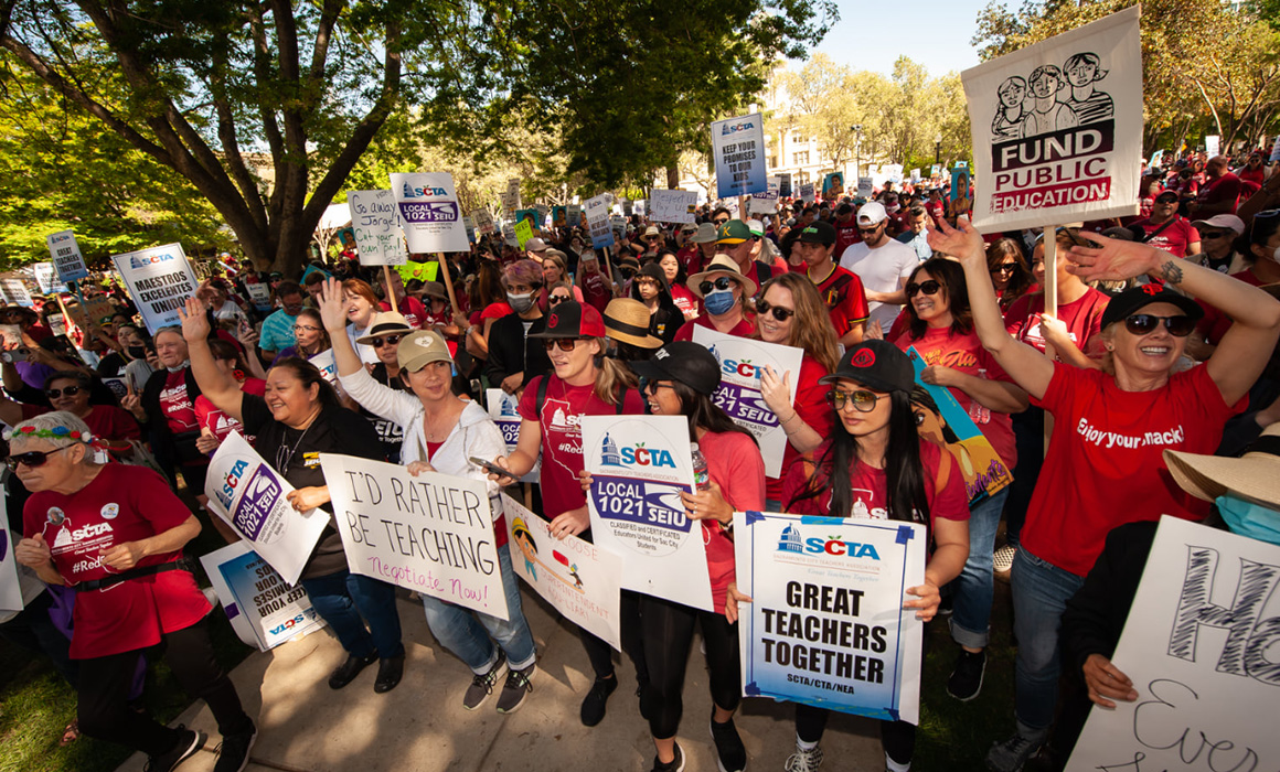 A large crowd of people holding up picket signs .