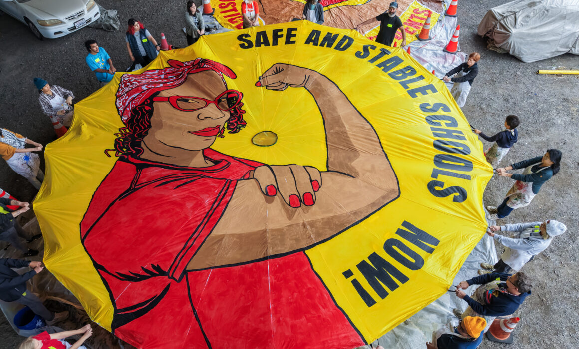 Educators, students, families and community allies helped paint this parachute, whose Rosie the Riveter is modeled after UTR member Miesha Gash.